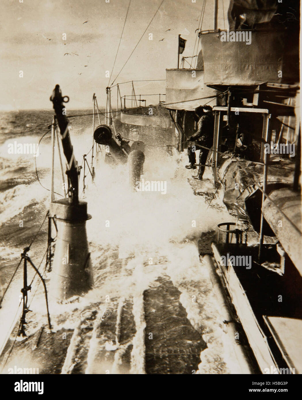 Una fotografia della HMAS Sydney, una nave della Marina Australiana, che attraversa mari accidentati. L'immagine cattura la potenza e la resilienza della nave mentre naviga attraverso acque impegnative, mostrando le capacità della nave durante le operazioni navali. Foto Stock