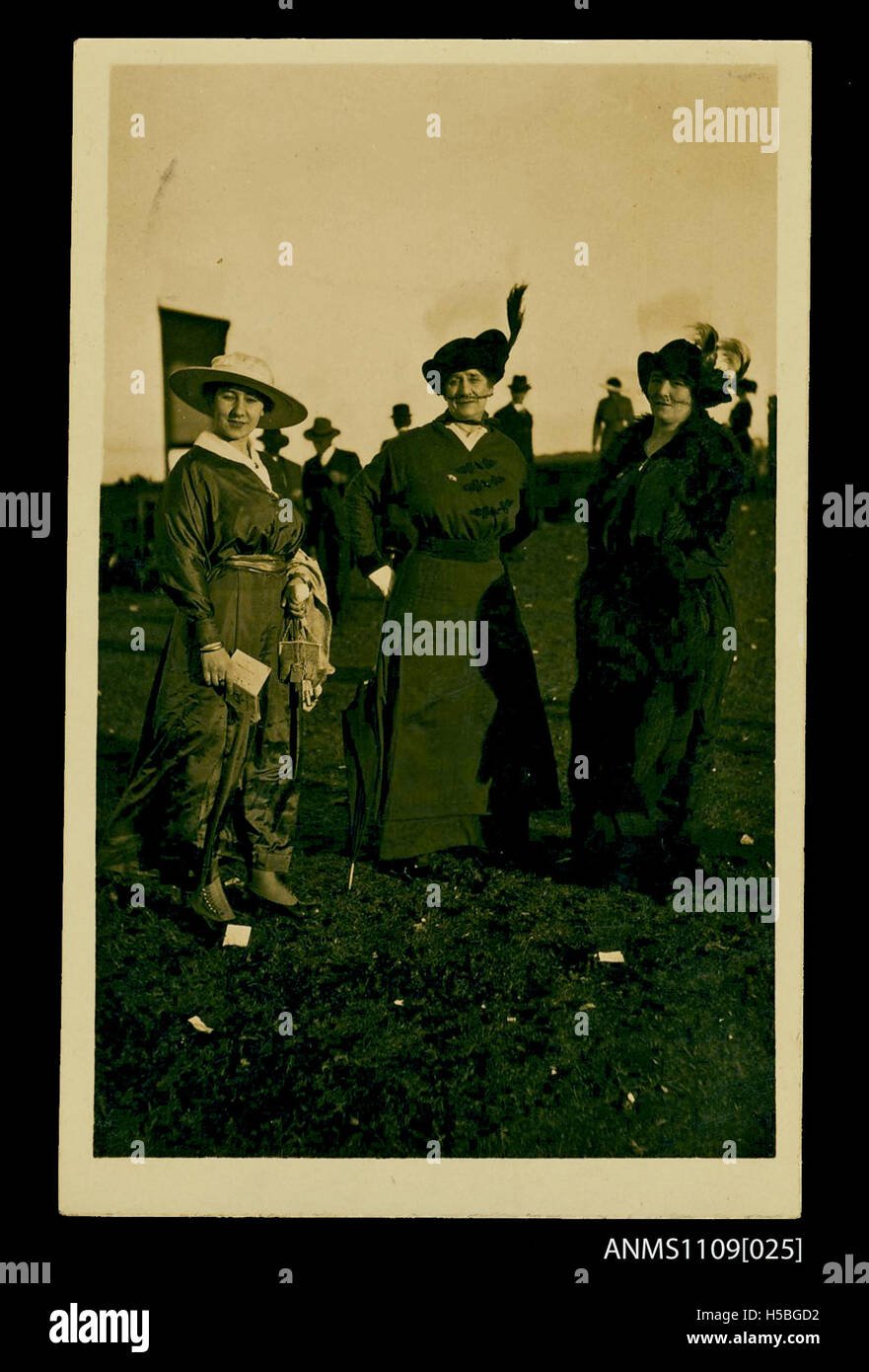 Una cartolina fotografica raffigurante tre donne, probabilmente scattate in un ippodromo, che cattura un momento durante un evento sociale all'inizio del XX secolo. Foto Stock