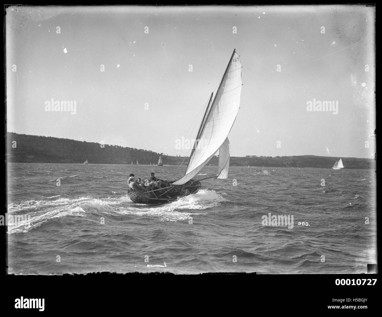 Questa immagine mostra uno yacht a vela completa nel porto di Sydney. La fotografia probabilmente cattura un evento a vela, come una regata, che si svolge nell'iconica via d'acqua di Sydney, in Australia. Foto Stock