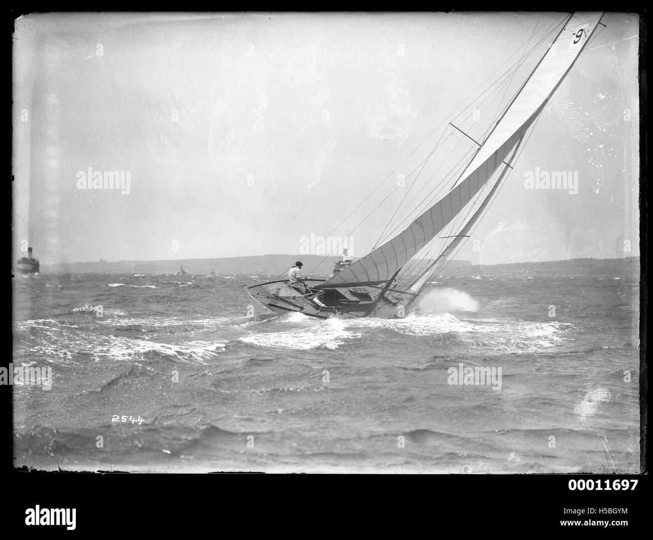 Uno yacht è visto navigare sul porto di Sydney, con l'iconica Sydney Opera House e Harbour Bridge visibili sullo sfondo. L'immagine cattura l'eleganza e la bellezza della navigazione in uno dei porti più famosi del mondo. Foto Stock