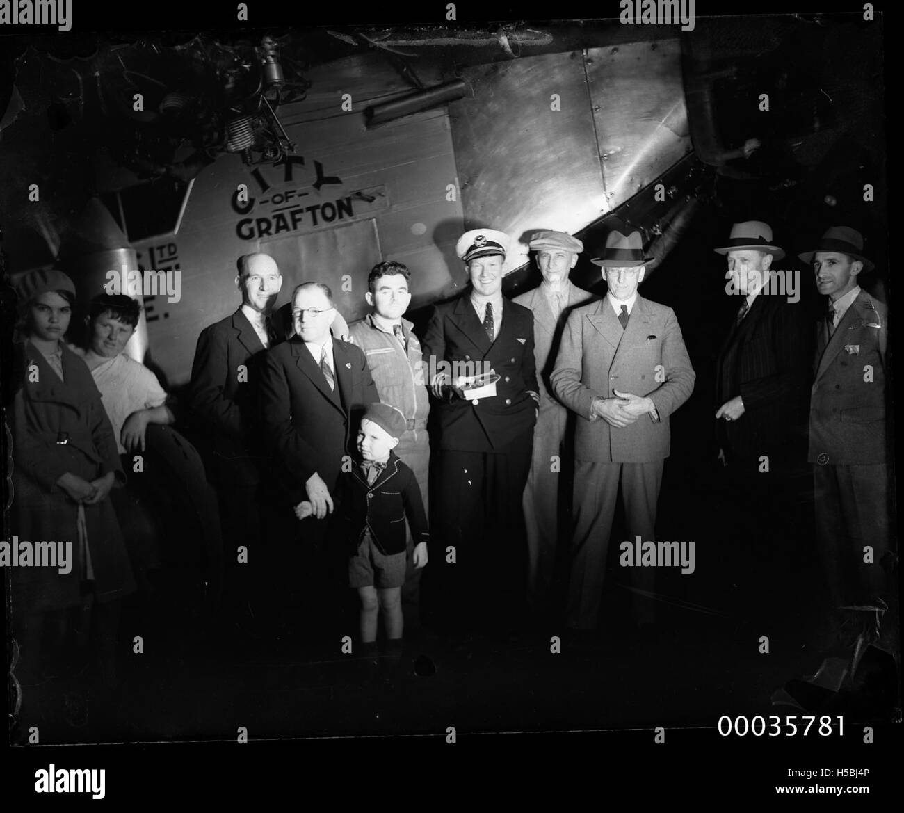 Questa fotografia cattura l'aereo della "città di Grafton" insieme al suo pilota e ai visitatori durante il periodo 1933-1935. L'aereo viene mostrato a terra con persone riunite intorno, evidenziando il significato della prima aviazione durante gli anni '1930 Foto Stock