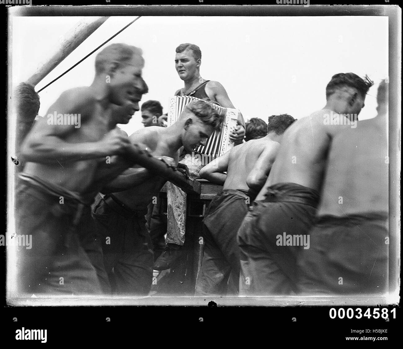 I marinai a bordo della nave MAGDALENE VINNEN sono ritratti insieme a un suonatore di fisarmonica. L'immagine evidenzia l'atmosfera rilassata e gli elementi culturali a bordo durante un viaggio marittimo. Foto Stock