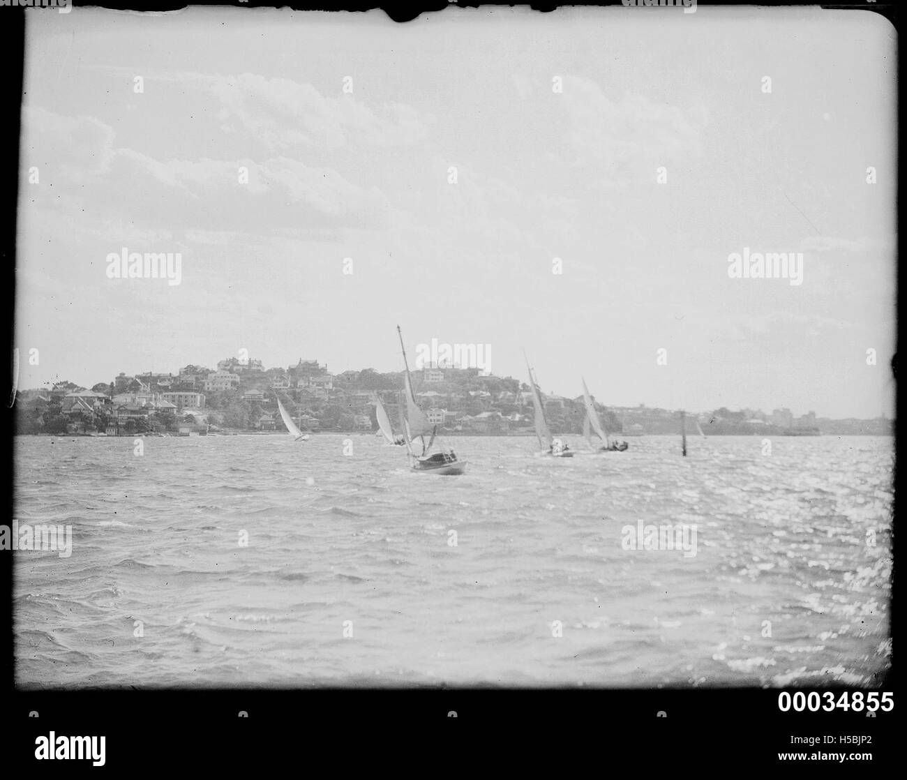 Una fotografia che mostra tre yacht di classe sei metri che corrono su un porto. L'evento mette in evidenza la navigazione competitiva, con particolare attenzione agli eleganti yacht e all'ambiente del porto durante una regata o una gara. Foto Stock