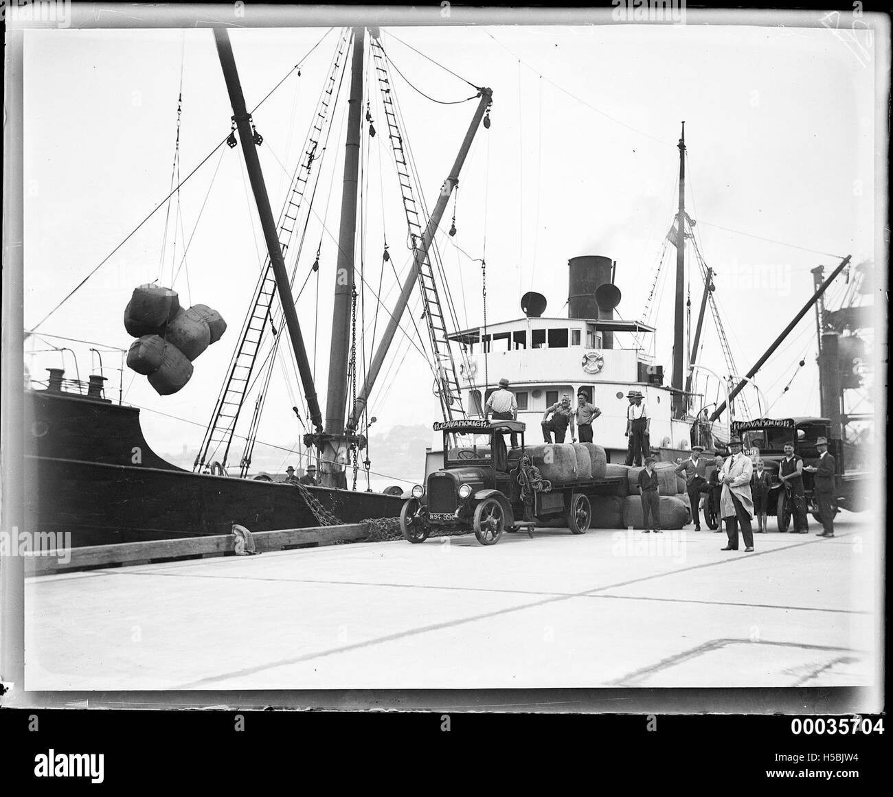 Questa fotografia mostra lo scarico di balle di lana dalla SS CANONBAR, una nave mercantile, tra il 1927 e il 1940. L'immagine riflette il commercio globale della lana, un'industria significativa durante questo periodo, in particolare nel mercato di esportazione australiano. Foto Stock
