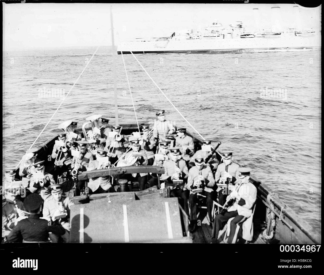 Questa fotografia mostra la banda militare ABC che si esibisce a bordo di una nave, accompagnata da un commentatore ABC. Scattata tra il 1933 e il 1951, questa immagine fa parte della COLLEZIONE HOOD, che riflette la collaborazione militare e mediatica in quel periodo. Foto Stock