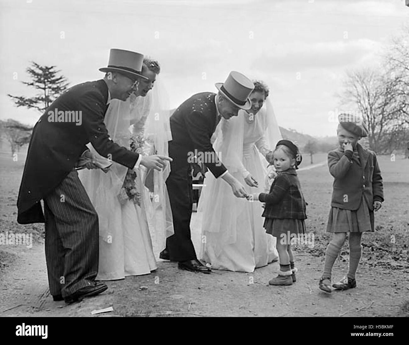 Una fotografia che cattura un doppio matrimonio a Llanrhaeadr, con Agnes della Morris e Mr. D. Noseworthy, e Joan Brown e Mr. F. Taking. L'evento è documentato con l'abbigliamento e la cerimonia della coppia. Foto Stock