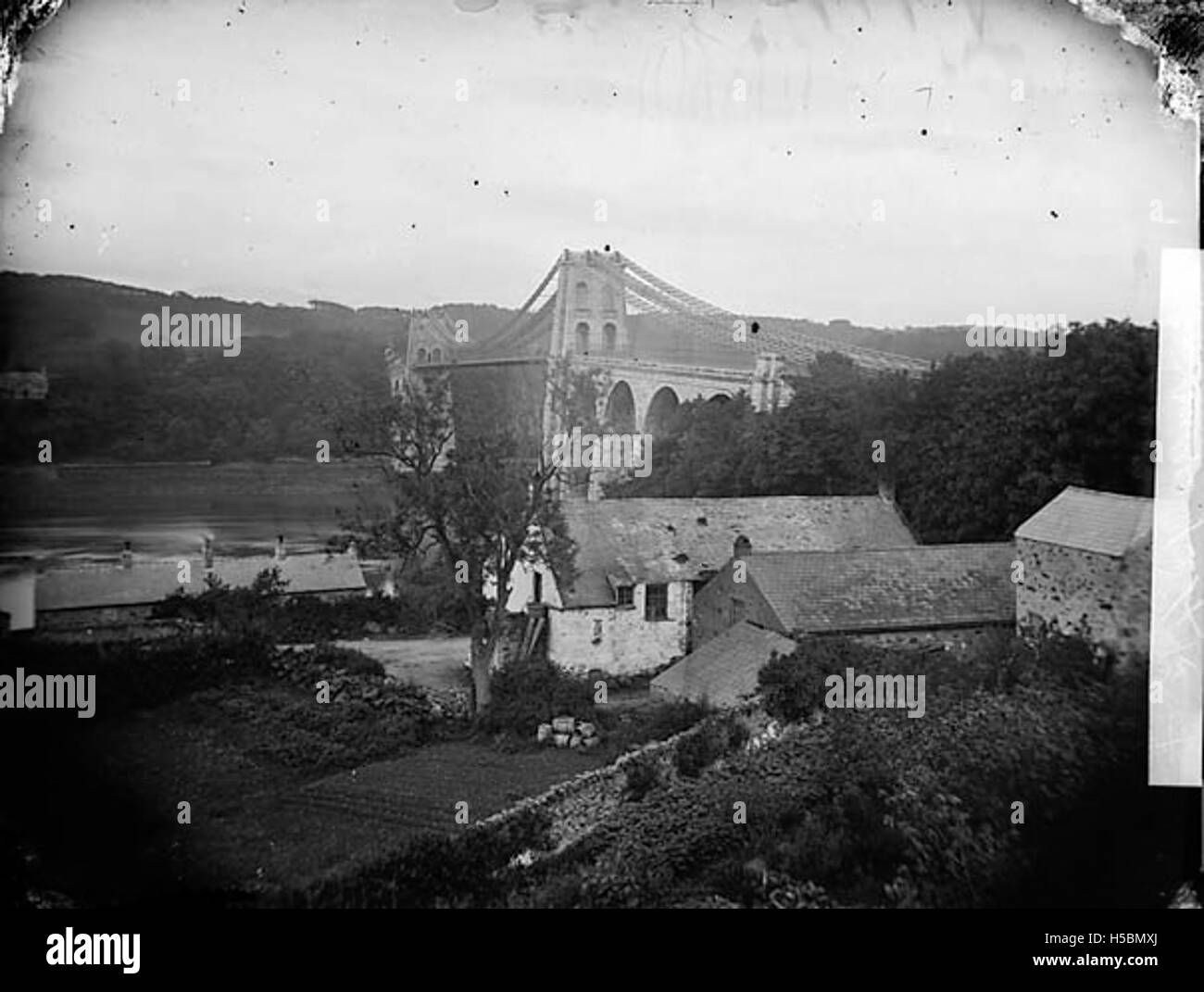 Il Menai Suspension Bridge, che collega l'isola di Anglesey alla terraferma gallese, è un pezzo iconico di ingegneria. Completato nel 1826, è stato progettato da Thomas Telford ed è un punto di riferimento significativo nel Regno Unito. Foto Stock