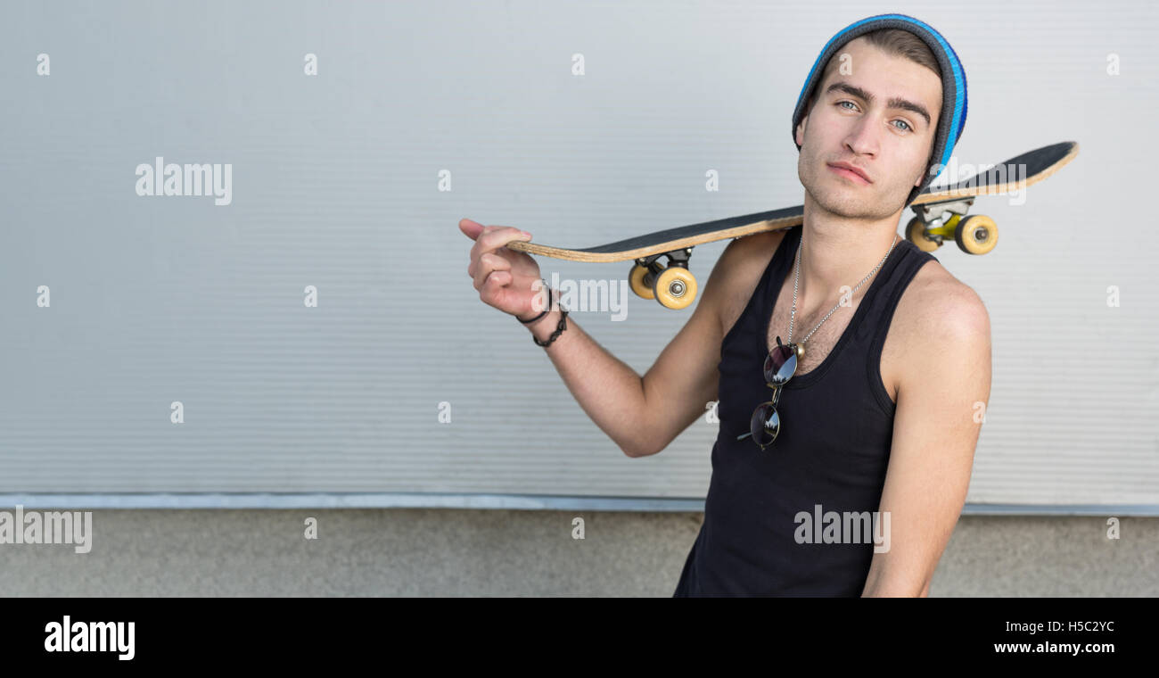 Ritratto di cool ragazzo adolescente con uno skateboard sulla sua spalla Foto Stock