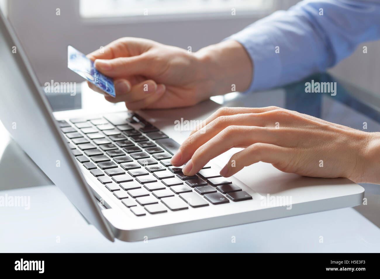 Donna mani tenendo la carta di credito e la digitazione sul portatile, il pagamento on-line su internet Foto Stock