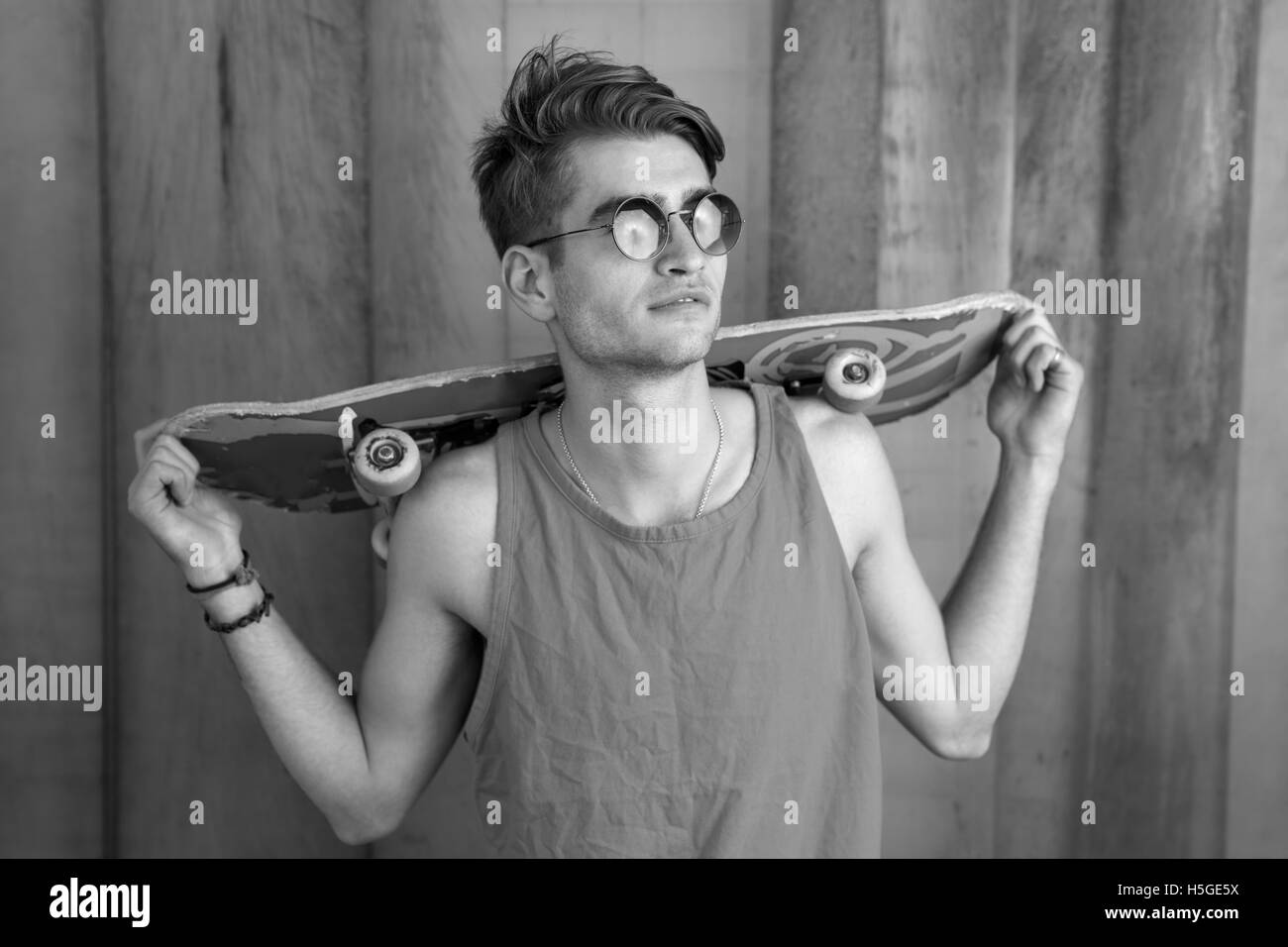 Attraente skater appoggiata contro il metallo serrande e tenendo la sua pensione Foto Stock