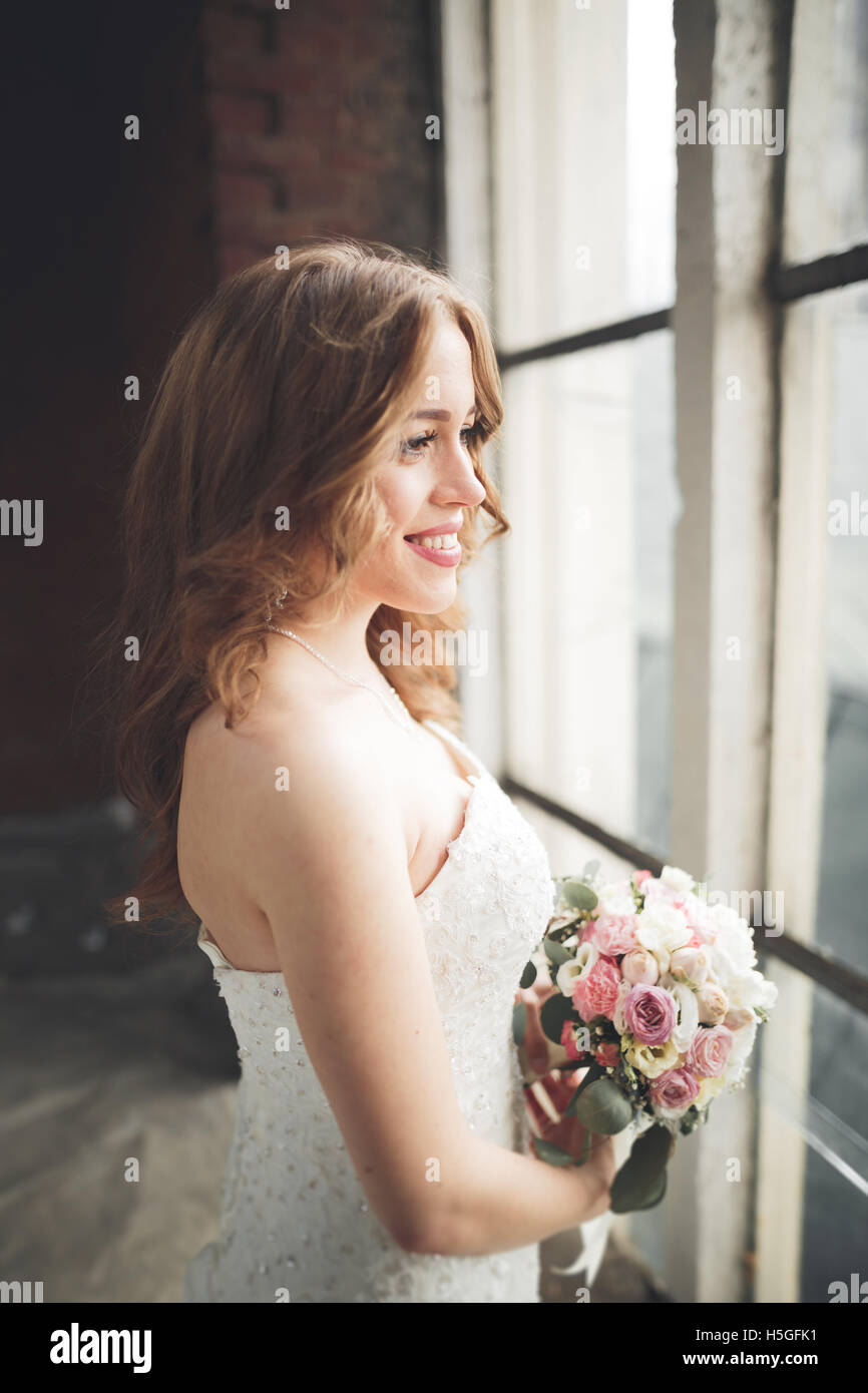 Elegante bellissimo matrimonio sposa in posa vicino al grande arco della finestra Foto Stock