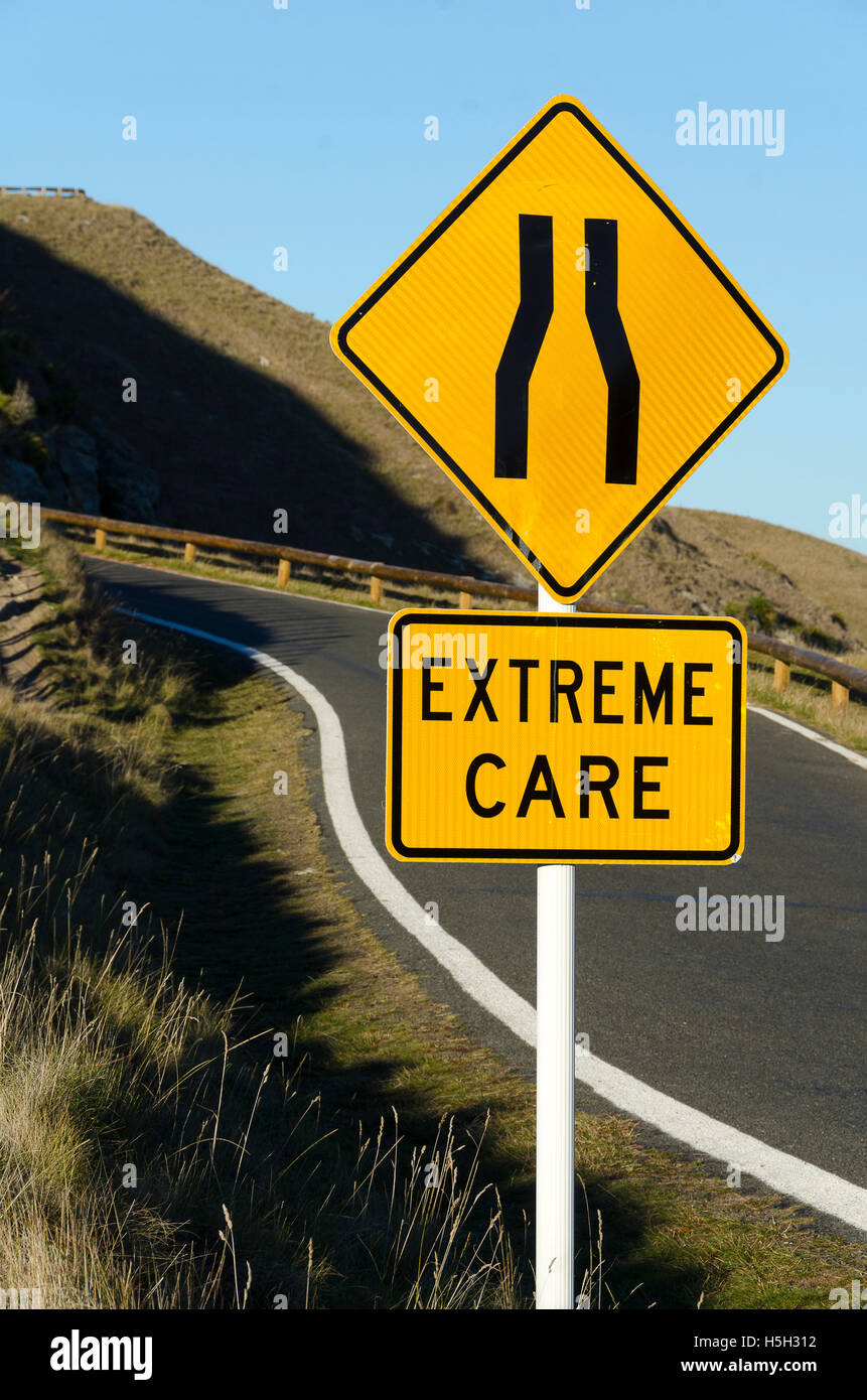 Strada tortuosa con "strada si restringe' e 'estrema cura' cartelli stradali, Te Mata picco, Hastings, Hawke Bay, Isola del nord, Nuova Zelanda Foto Stock