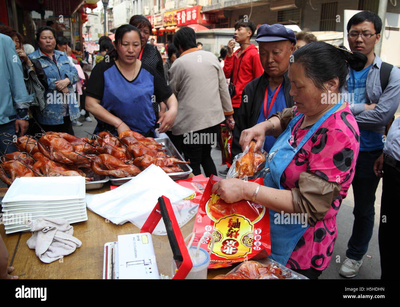 Un uomo cinese è di acquistare da una donna avvolta pollo alla griglia su Qibao Old Street. Pechino, Cina. 26.04.2016 Foto Stock