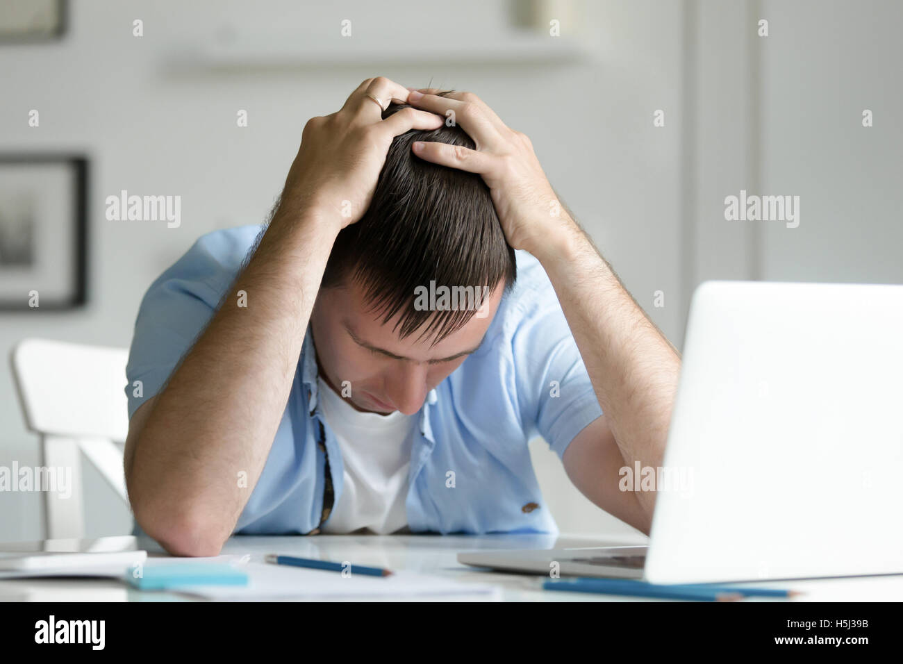 Ritratto di uomo afferrando la sua testa nella disperazione nei pressi di laptop Foto Stock