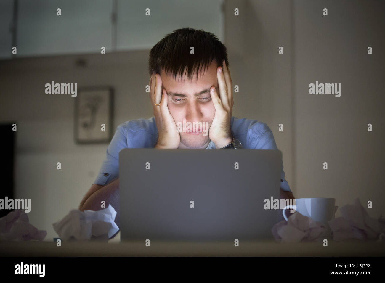 Ritratto di un uomo alla scrivania vicino al computer portatile, a tarda notte Foto Stock