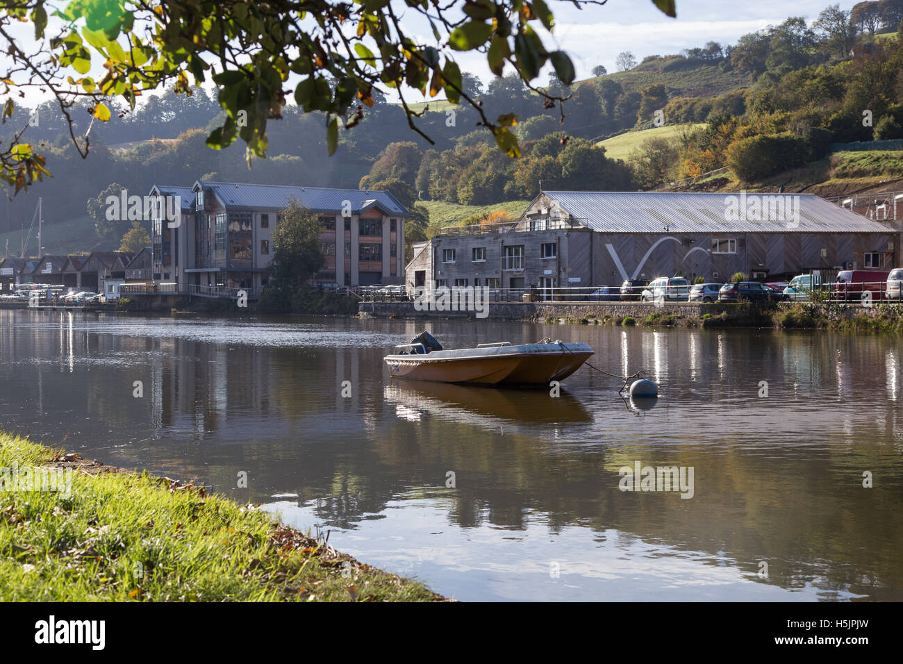 Una piccola barca e la proprietà a fianco del fiume Dart, a Totnes, Devon Foto Stock