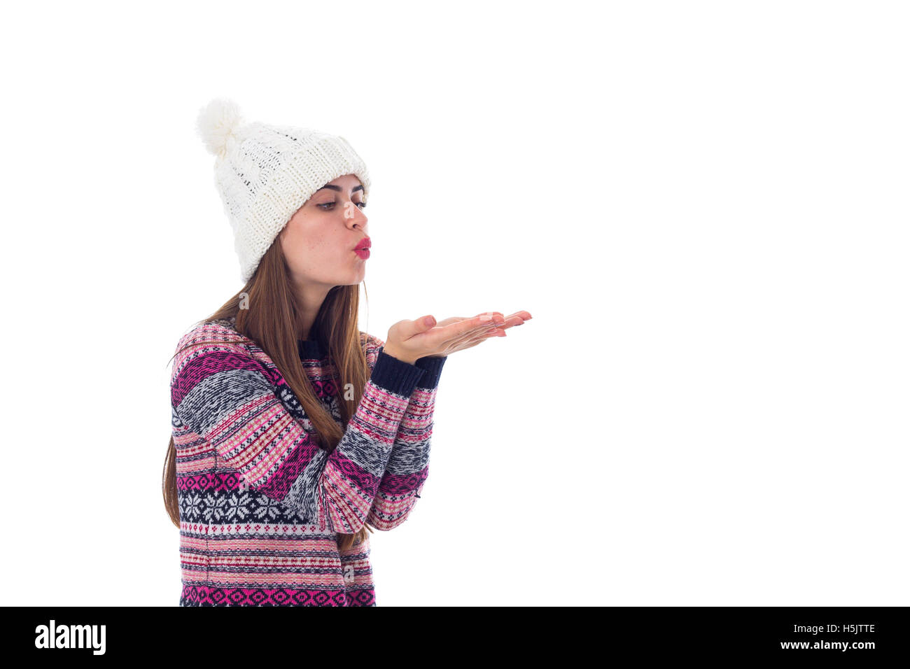 Donna in giacca e cappello bianco soffiando Foto Stock