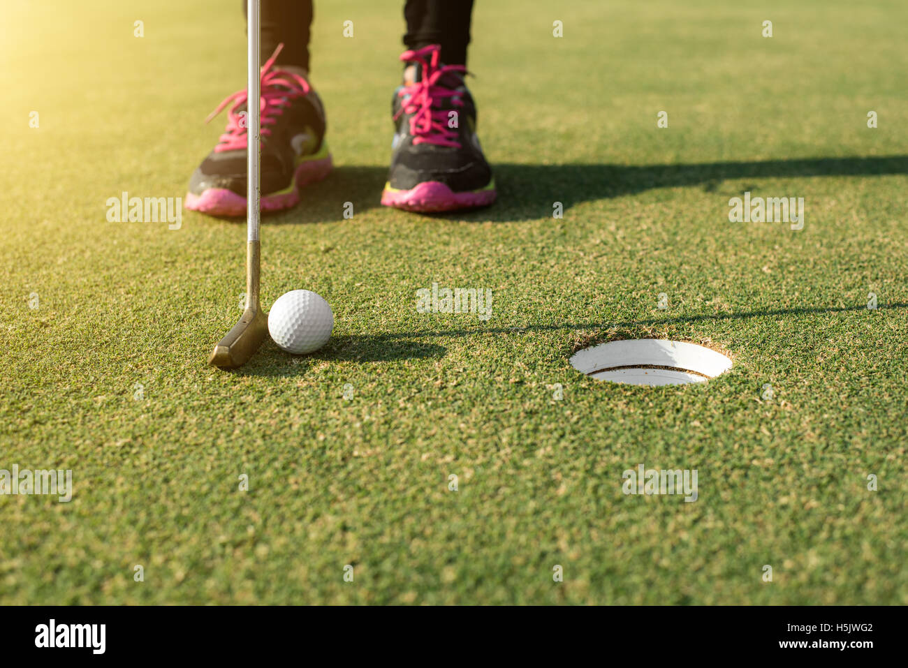 Giocatore di golf al putting green mettendo la pallina da golf in un foro. Golf sport concept. Foto Stock