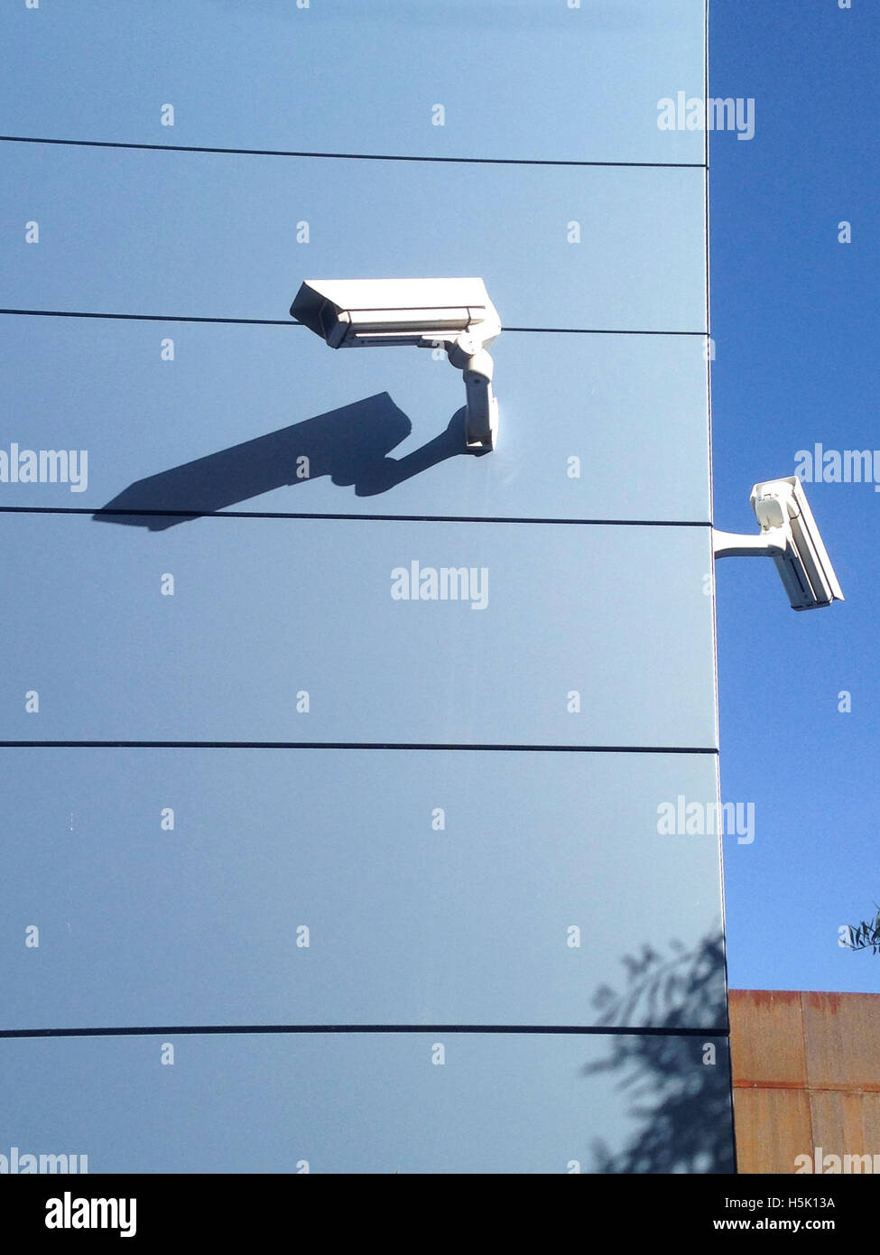 Due videocamere di sicurezza su edificio blu corner Foto Stock