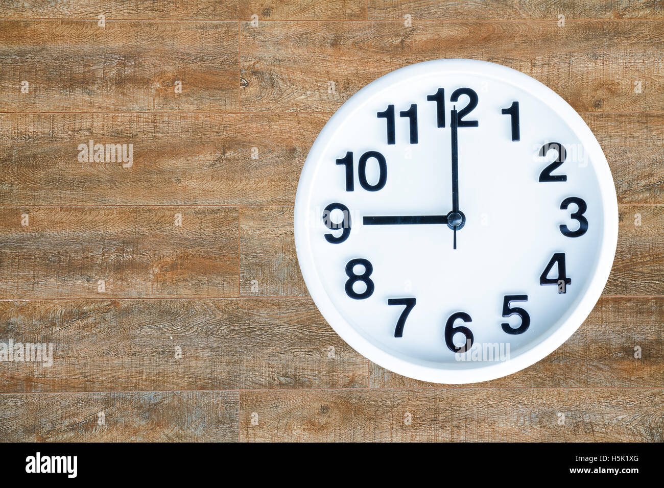 Mostra orologio 9 am o pm su uno sfondo di legno con copia spazio. tracciato di ritaglio di immagine. Foto Stock