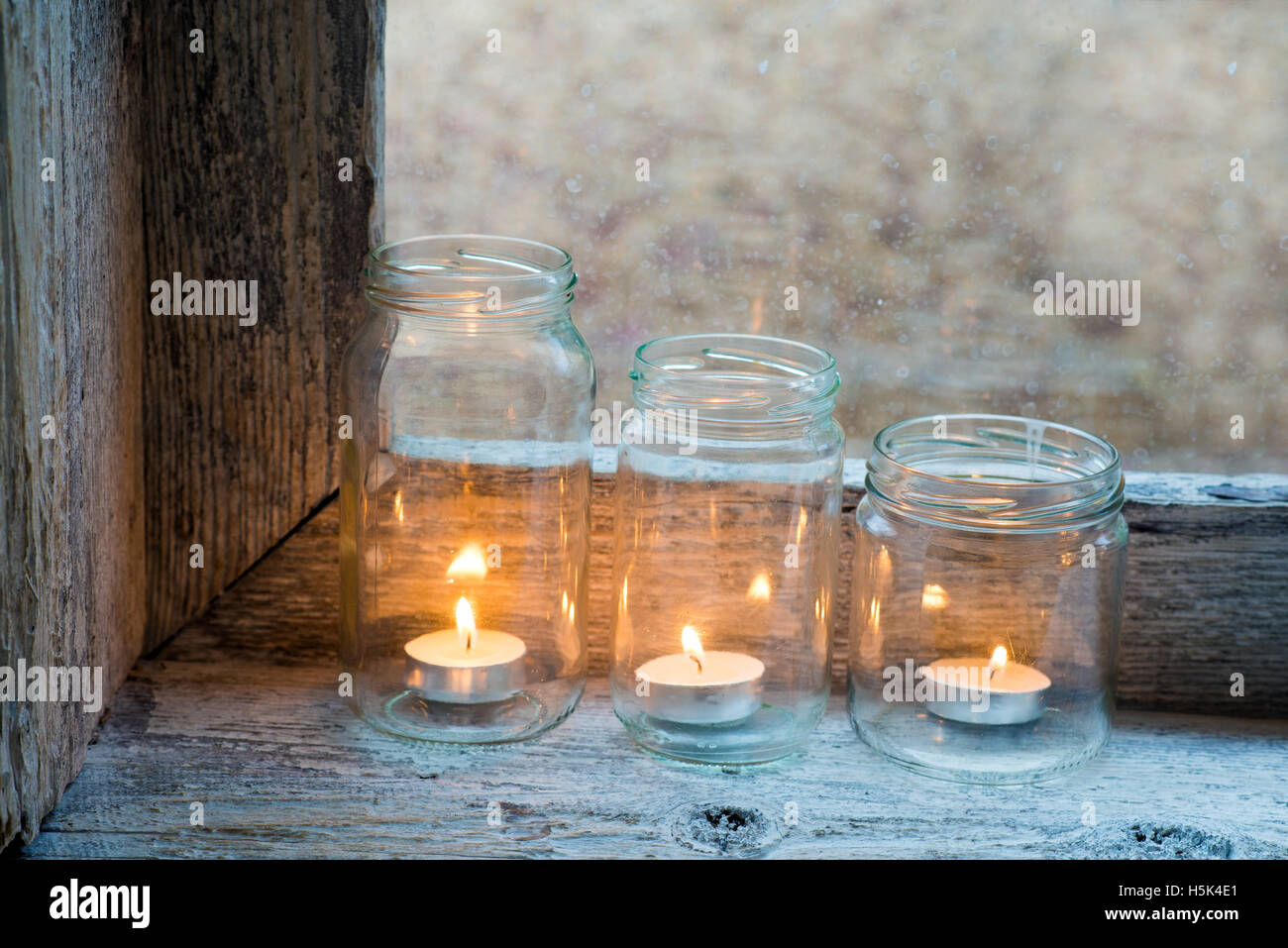 Candele in tre vasi di vetro su un davanzale Foto Stock