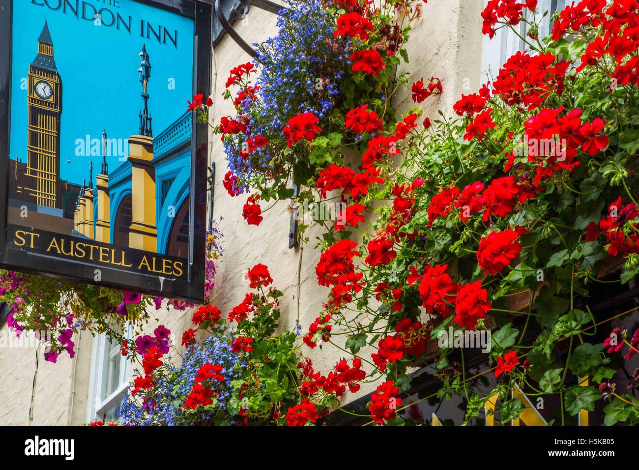 Un segno di pub a Padstow, Cornwall - London Inn con pareti di colore bianco e rosso e blu nei cestini appesi al di fuori Foto Stock