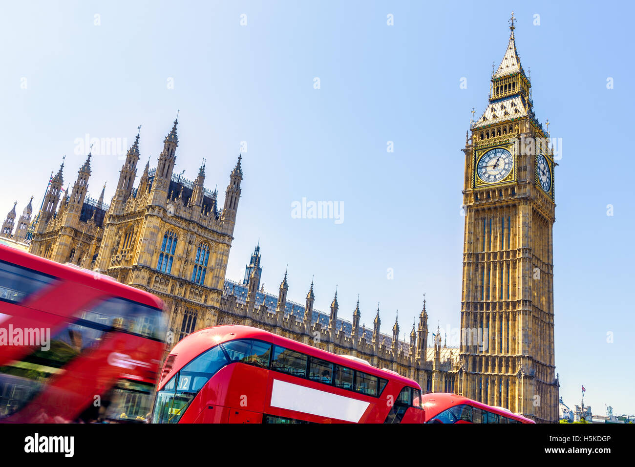 Il Big Ben e il Parlamento di Londra con autobus rossi passando da in movimento su un giorno senza nuvole Foto Stock