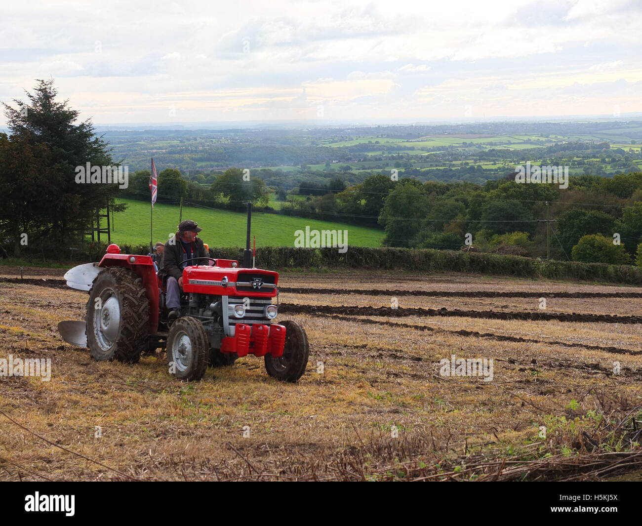 Agricoltore battenti bandiera dell'Union Jack dal suo trattore. Prese a Ashover Match di aratura svoltasi a Highoredish Farm, Derbyshire. Foto Stock