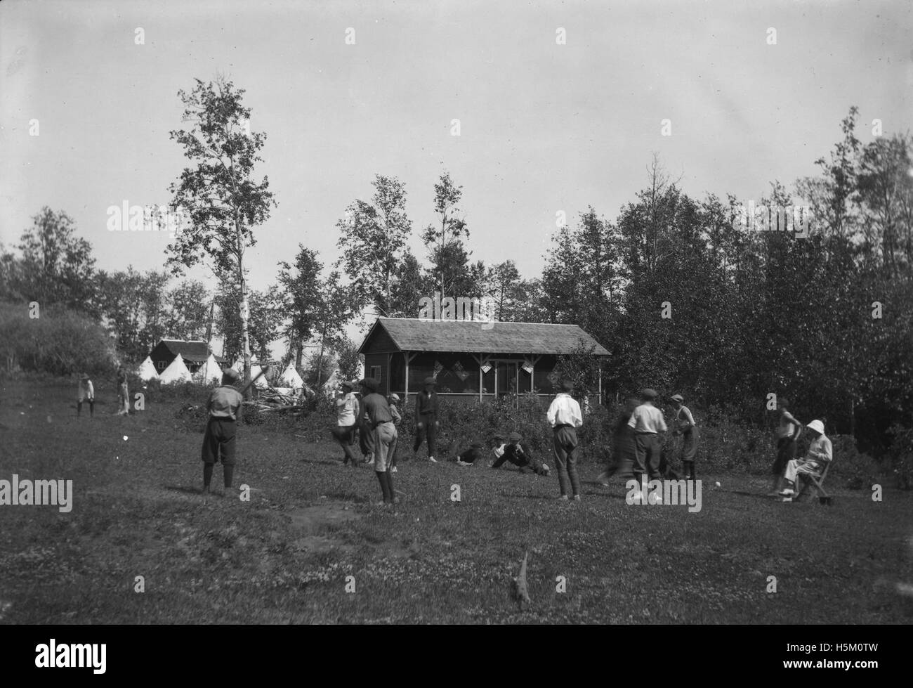 Questa foto mostra un gruppo di ragazzi che giocano a baseball in un campo estivo. L'immagine cattura gli aspetti ricreativi e sociali della vita del campo, con lo sport come parte integrante dell'esperienza del campo. Foto Stock Questa foto mostra un gruppo di ragazzi che giocano a baseball in un campo estivo. L'immagine cattura gli aspetti ricreativi e sociali della vita del campo, con lo sport come parte integrante dell'esperienza del campo. Foto Stock