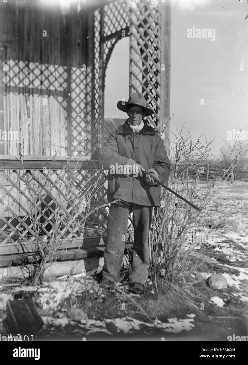 Questo ritratto raffigura un cowboy di Bowden, Alberta, che mostra l'abbigliamento tradizionale e lo stile di vita aspro dei cowboy nel Canada dei primi anni del XX secolo. L'abbigliamento dettagliato del cowboy riflette il patrimonio rurale della regione. Foto Stock