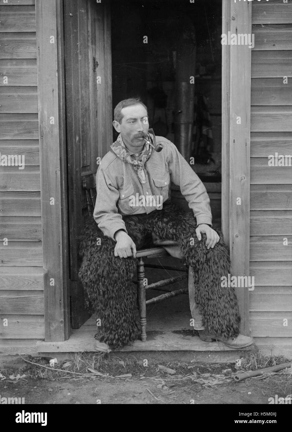 Questo ritratto cattura un cowboy di Bowden, Alberta, che indossa cappellini di pelliccia L'immagine riflette la cultura dell'allevamento del Canada all'inizio del XX secolo, mostrando l'abbigliamento e gli strumenti dei cowboy che lavoravano nei ranch della regione dell'Alberta. Foto Stock