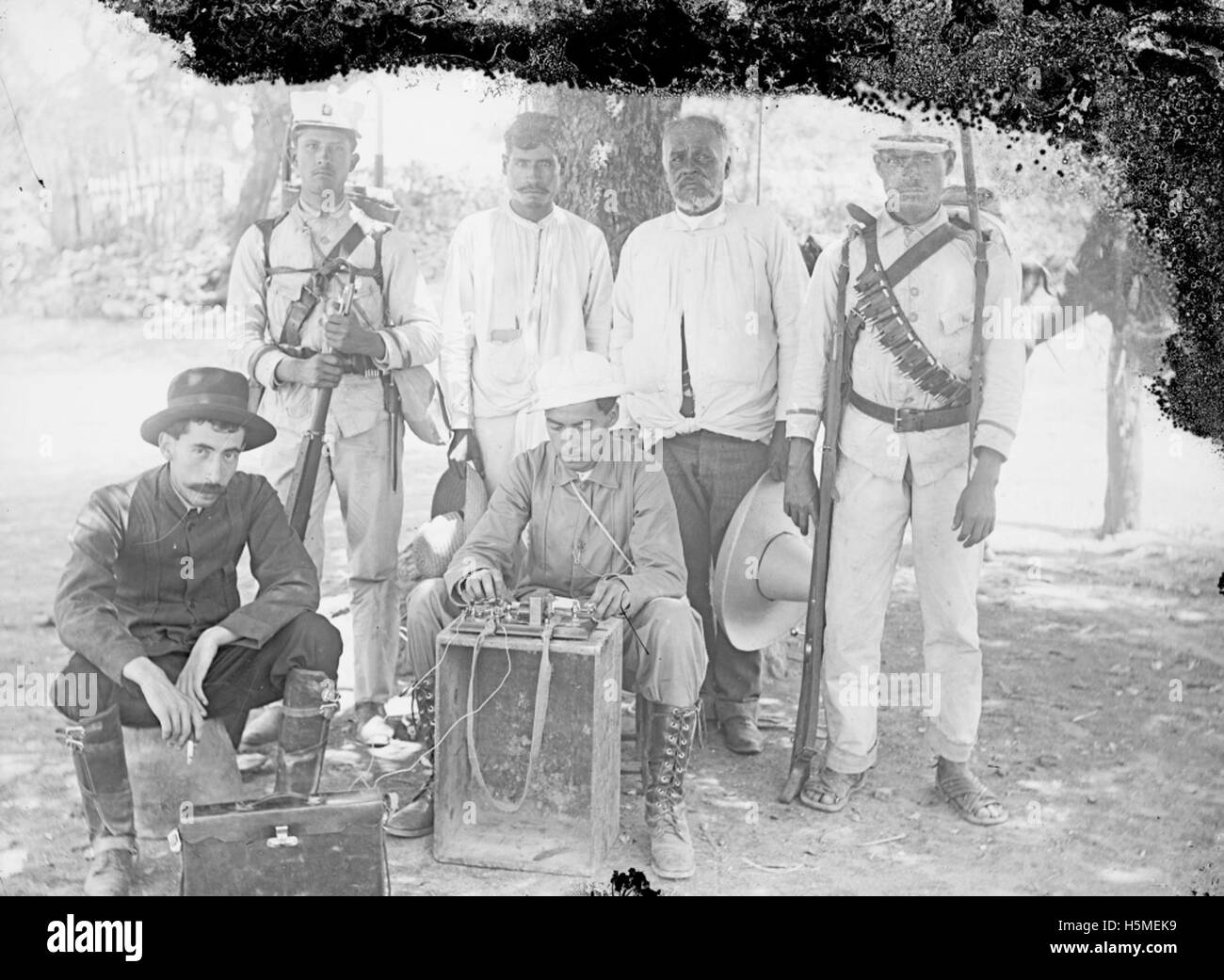 Questa immagine raffigura probabilmente soldati durante la rivoluzione messicana, mostrati con armi da fuoco e una macchina telegrafica, evidenziando il ruolo della comunicazione e della tecnologia militare nel conflitto. Foto Stock