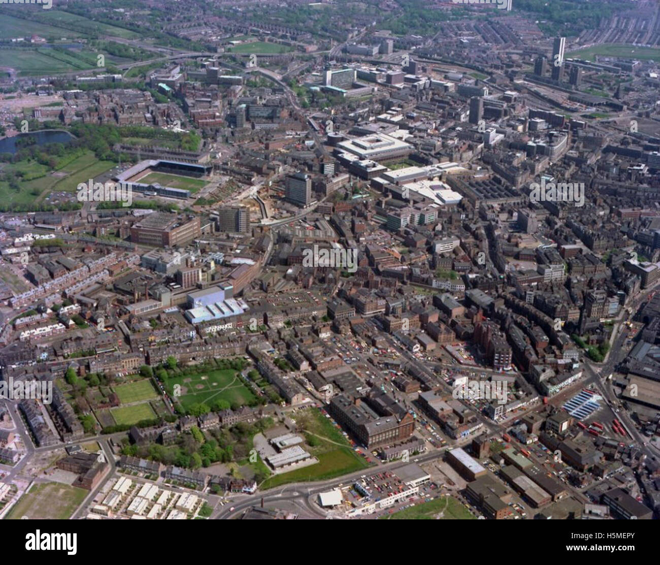Questa fotografia aerea del 1977 mostra un'ampia vista del centro di Newcastle, evidenziando aree chiave come Blandford Square, Blenheim Street, Eldon Square e Grainger Market. Cattura anche le birrerie di Newcastle, St James' Park e strade importanti come Waterloo Street e Westgate Road. Foto Stock