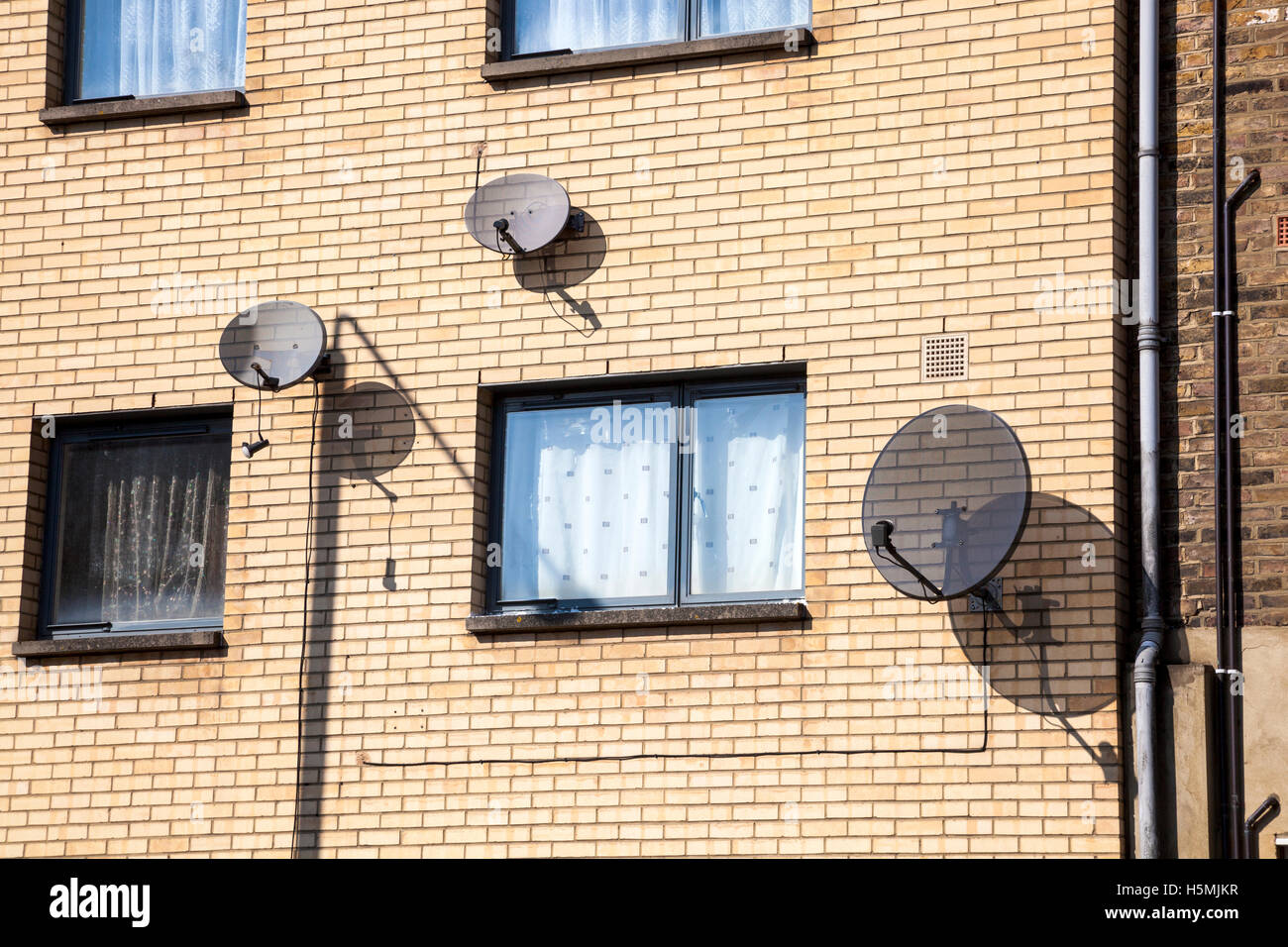 Antenne paraboliche appeso alla parete di un edificio residenziale di Londra, Regno Unito Foto Stock