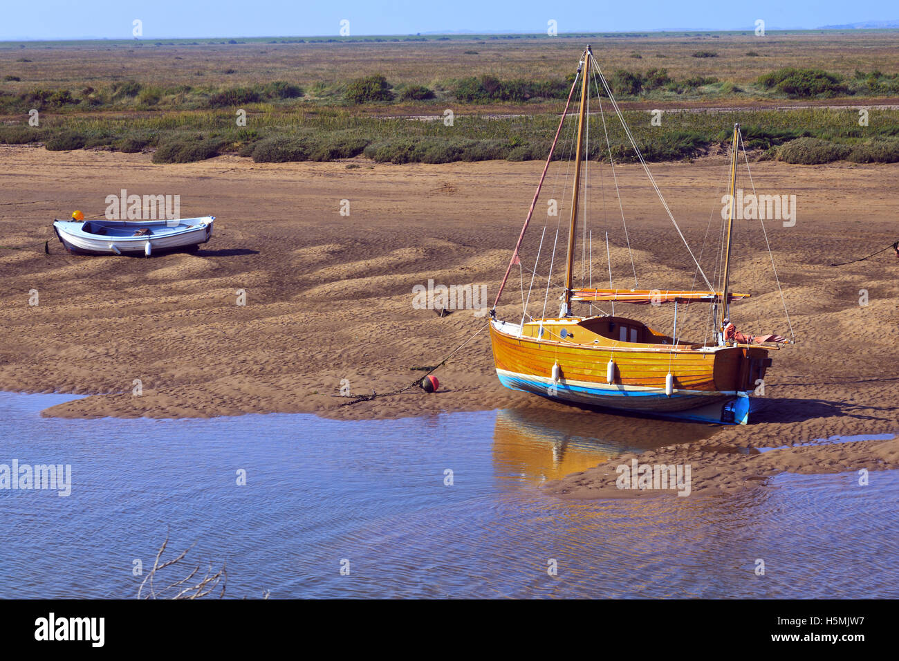Barche a bassa marea a Burnham-Overy-Staithe sulla costa di Norfolk, Inghilterra, Regno Unito Foto Stock