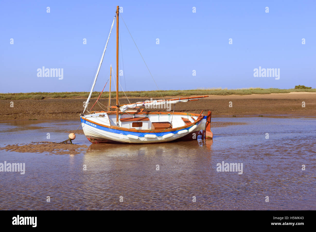 Barca stesa sulla chiglia a bassa marea a Burnham-Overy-Staithe sulla costa di Norfolk, Inghilterra, Regno Unito Foto Stock