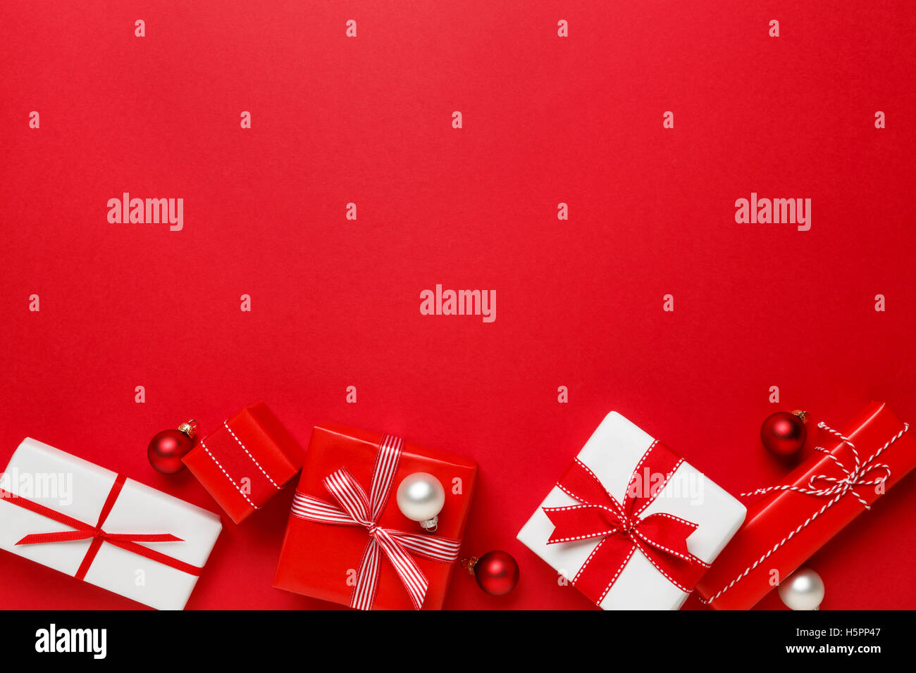 Regali di natale presenta su sfondo rosso. Semplice, classic, Red & White avvolto confezioni regalo con nastro archi bordo orizzontale. Foto Stock