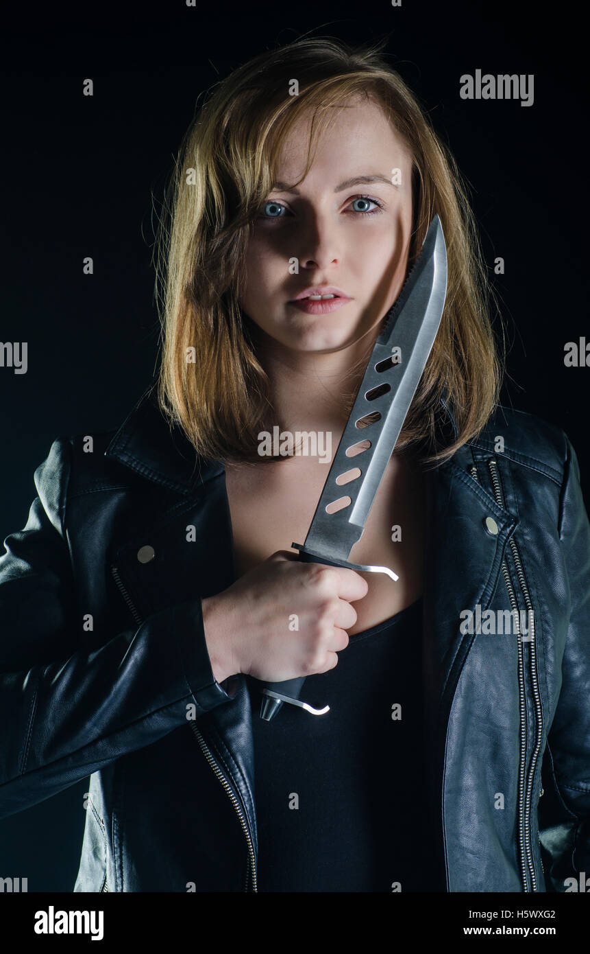 Femmina bionda tenendo un pugnale nel buio Foto Stock