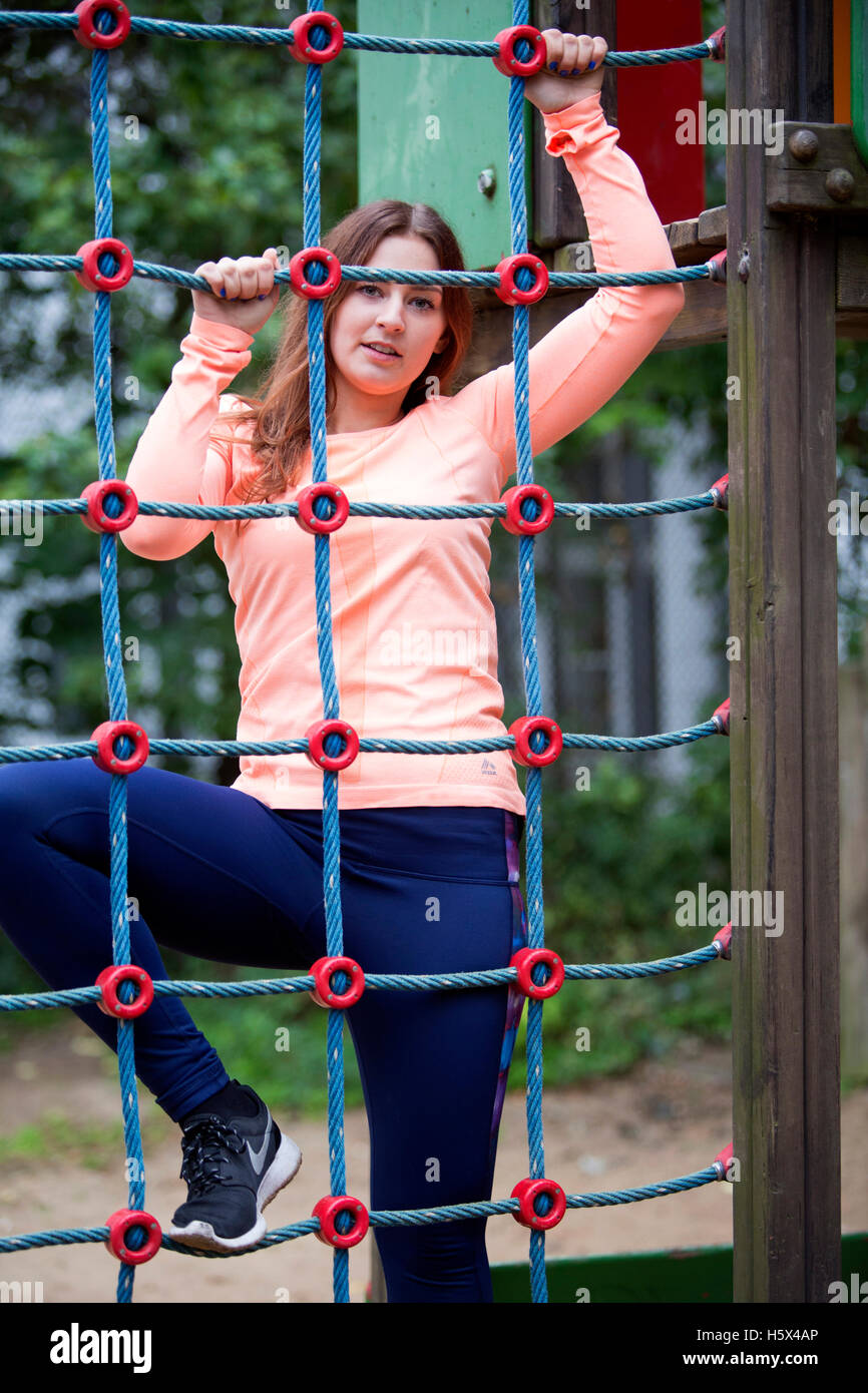 Giovane bella donna sportivo salendo su un net all'aperto Foto Stock