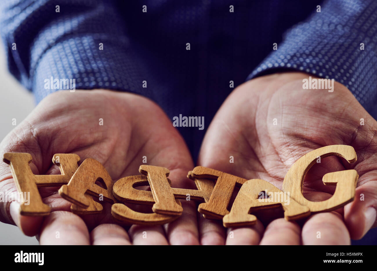 Lettere di legno costituente la parola hashtag ha messo nelle mani di un giovane uomo caucasico Foto Stock