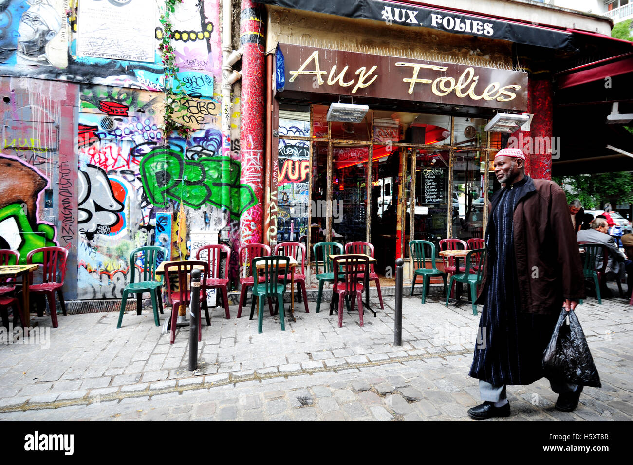 Un uomo a piedi nella parte anteriore del 'Aux Folies' café nel quartiere di Belleville, Parigi, Francia Foto Stock