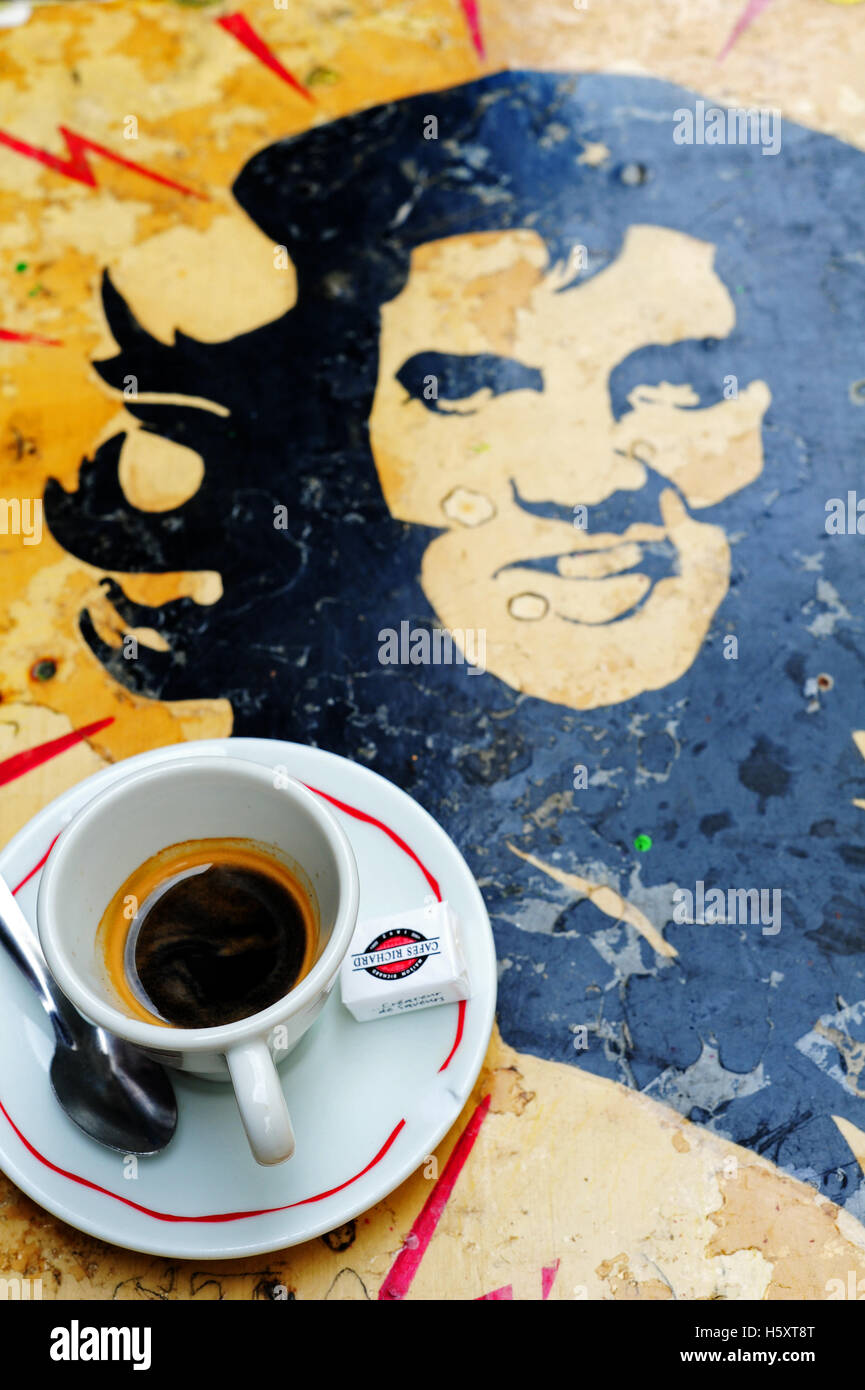 Una tazza di caffè su una tabella con una illustrazione di un Elvis-Che Guevara in un bar nel quartiere di Belleville, Parigi, Francia Foto Stock
