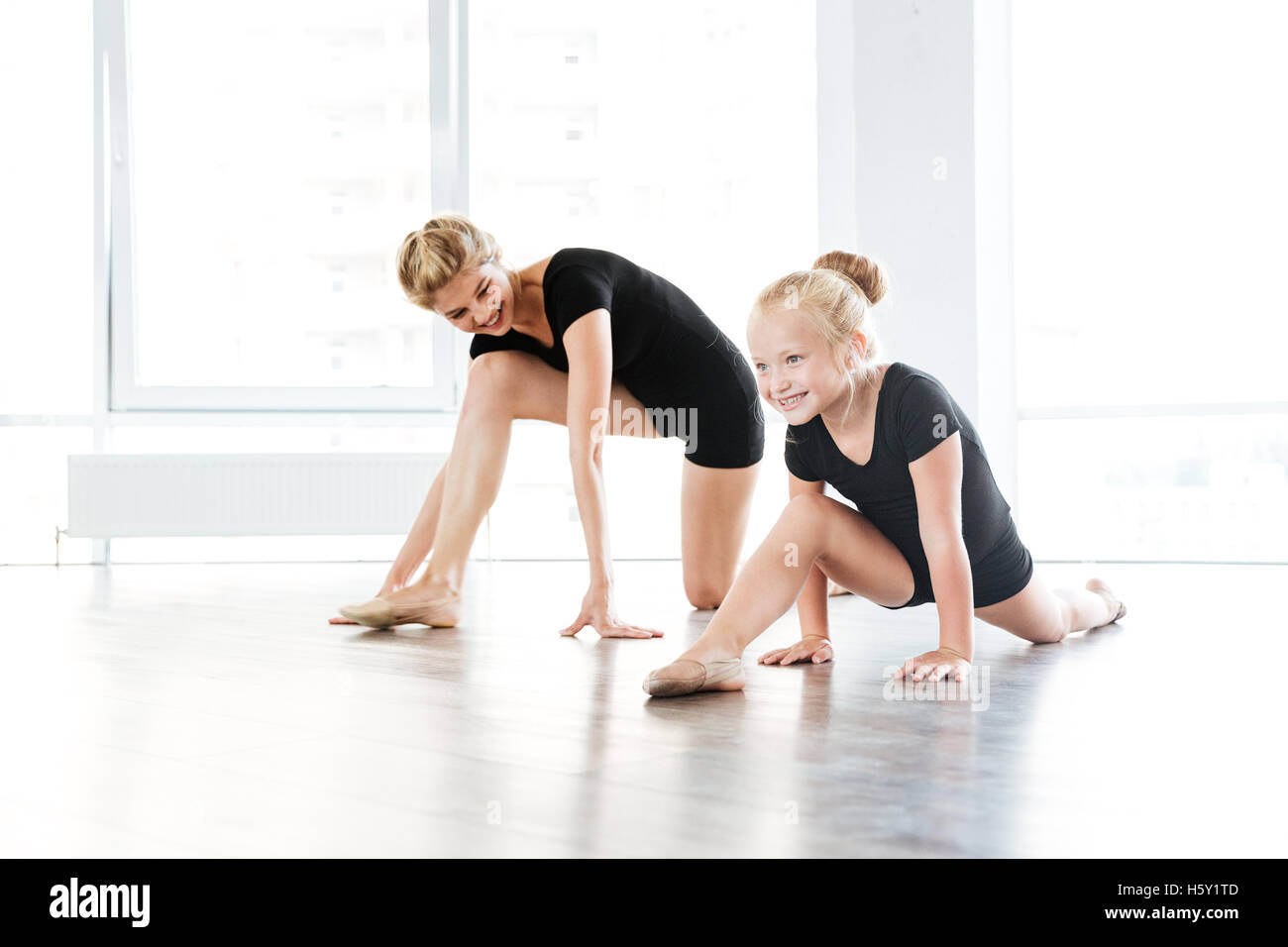 Allegro poco bellissima ballerina e il suo insegnante lo stiramento sul pavimento nella scuola di danza Foto Stock
