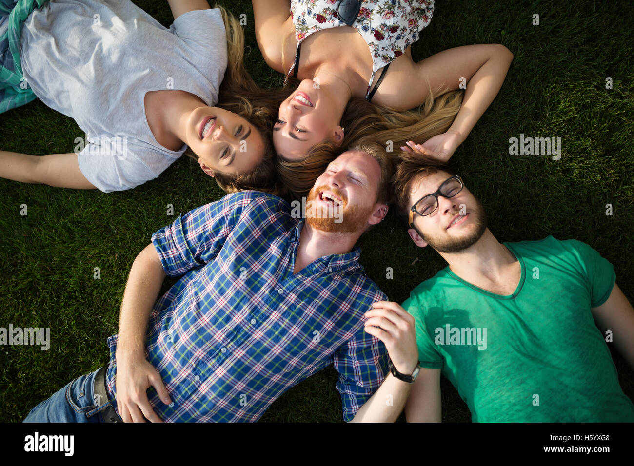 Gruppo di persone felici sdraiati sull'erba Foto Stock