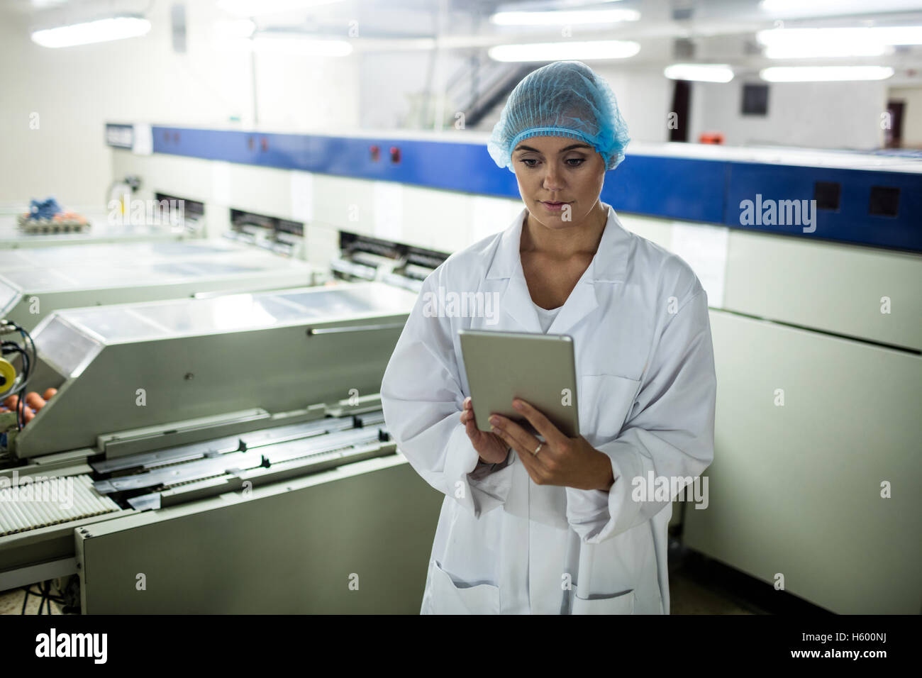 Personale femminile con tavoletta digitale accanto alla linea di produzione Foto Stock