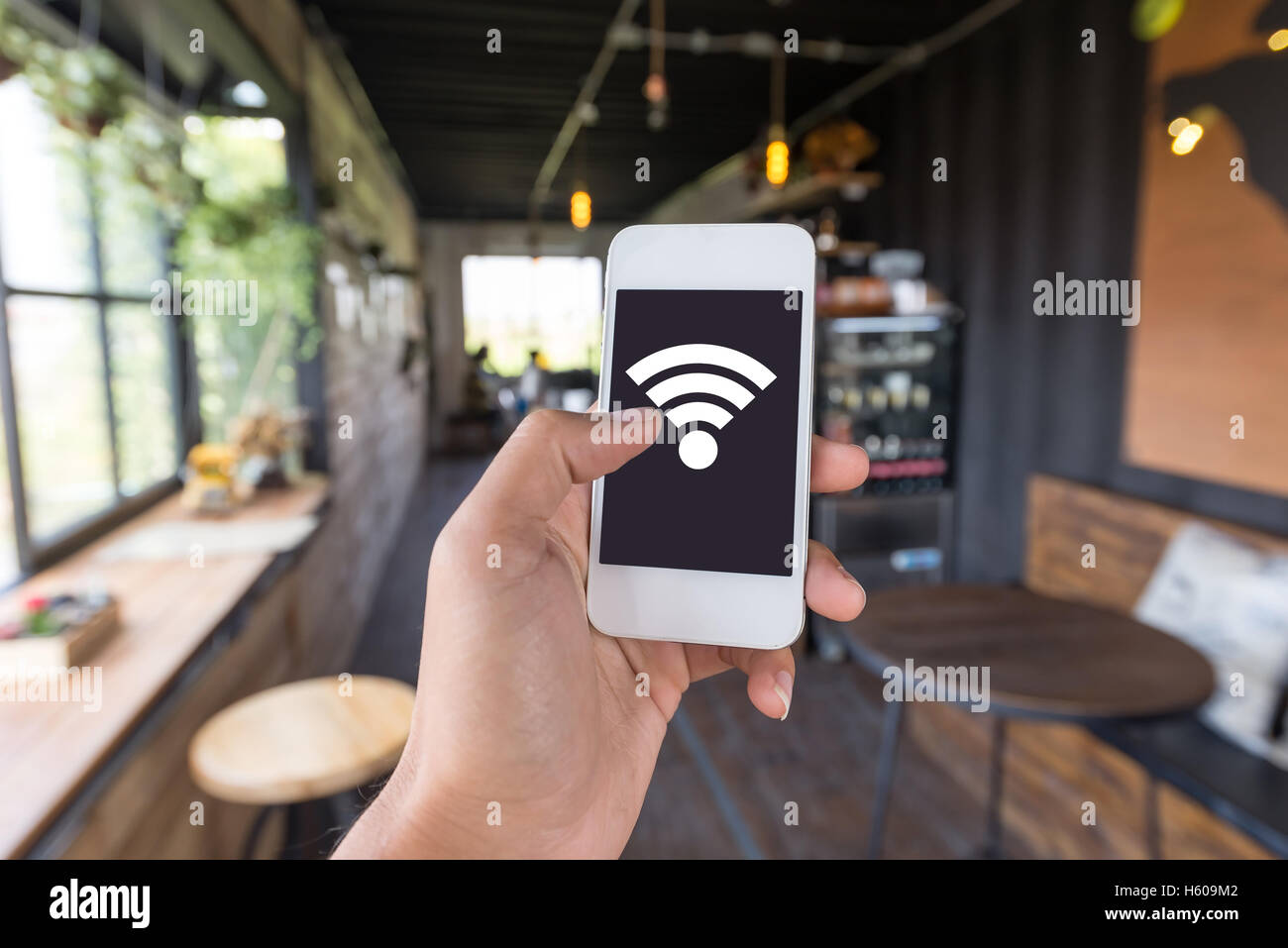 Mano utilizzando Smart phone nel negozio di caffè nella caffetteria dispone di connessione wifi gratuita per il cliente di essere possibile utilizzando Connetti rete sociale Foto Stock