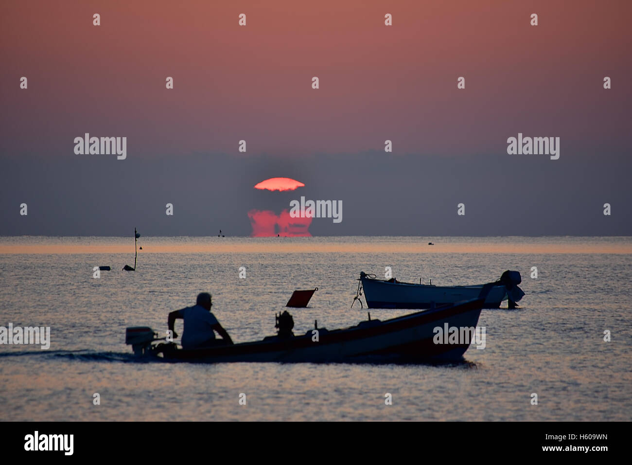 Fisherman silhouette in rosso sunrise, Sud Italia. Foto Stock