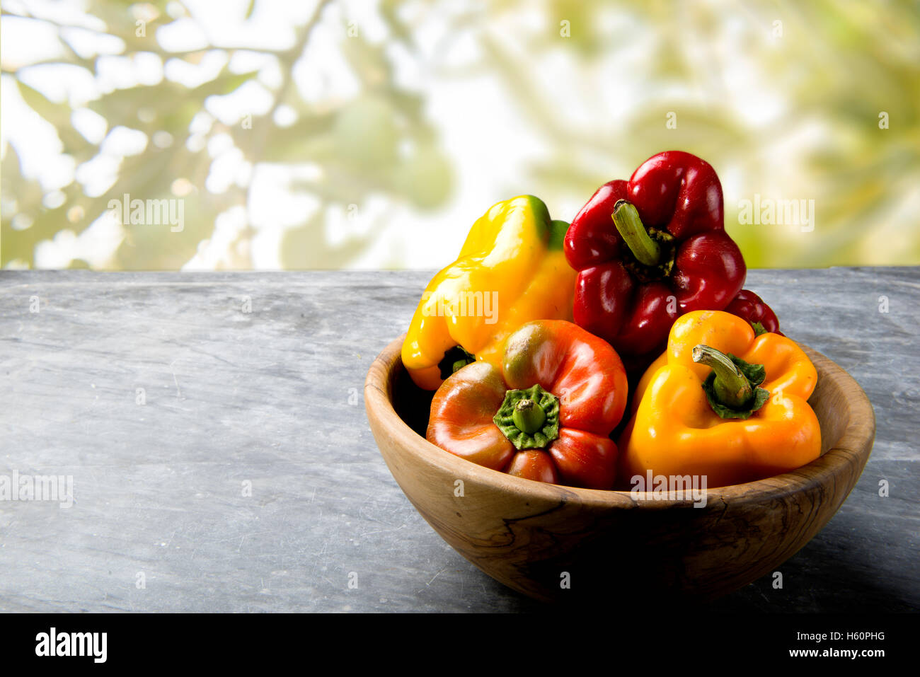 Ciotola di legno colorato e peperoni bell su un marmo nero Foto Stock