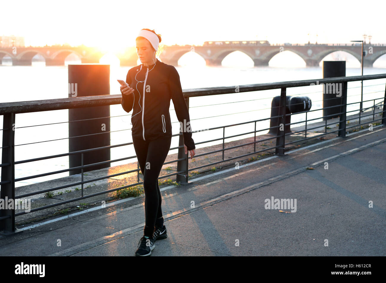 Donna che cammina montare telefono fitness banca del fiume alba Foto Stock