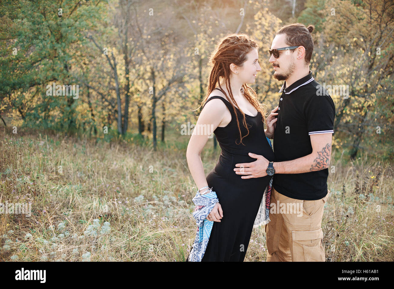 L uomo e la donna incinta abbracciando tenendo le mani sullo sfondo di una natura selvaggia, l'autunno. storia d'amore Foto Stock